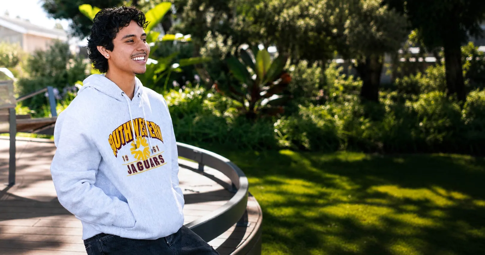 student on campus smiling while wearing Southwestern Jaguars hoodie